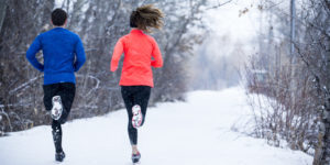 Couple running in snowy woods.